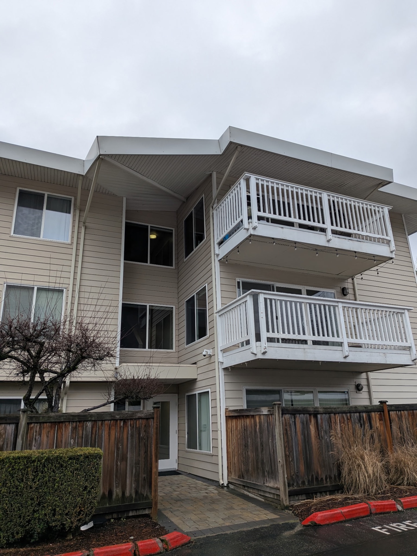 Low-angle view of a multi-story residential building with a flat TPO roof and wide white overhang with soffit repair by P.J Roofing LLC