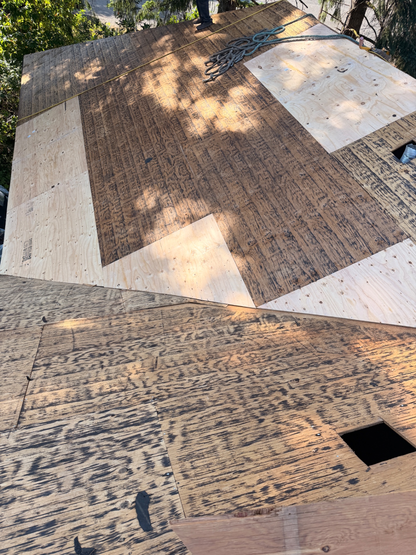 Roof decking under repair with sections of new plywood installed by P.J. Roofing LLC