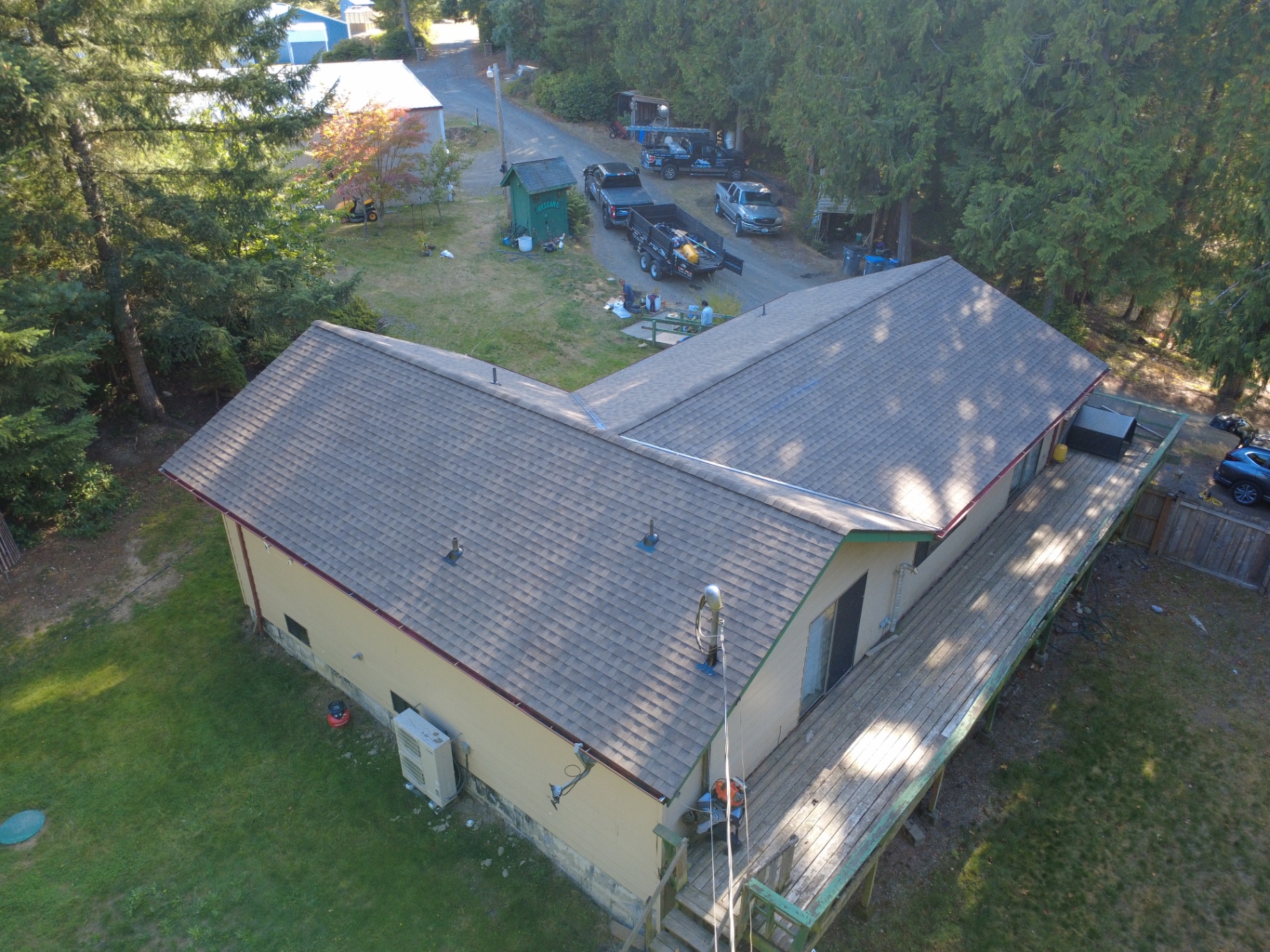 Wide aerial view of a completed roof and decking replacement on a wooded Silverdale home