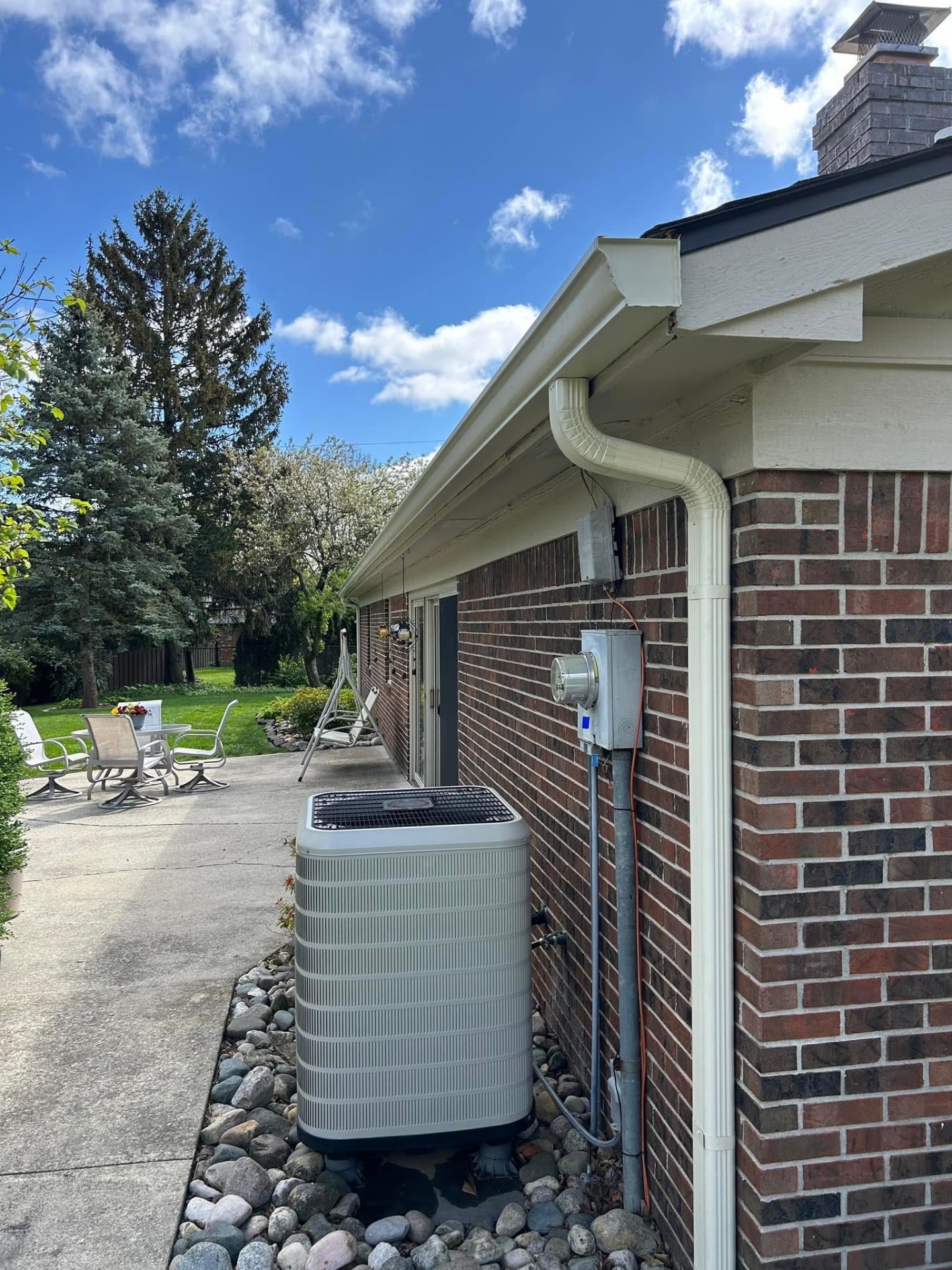 New white gutter and downspout installed on a brick home