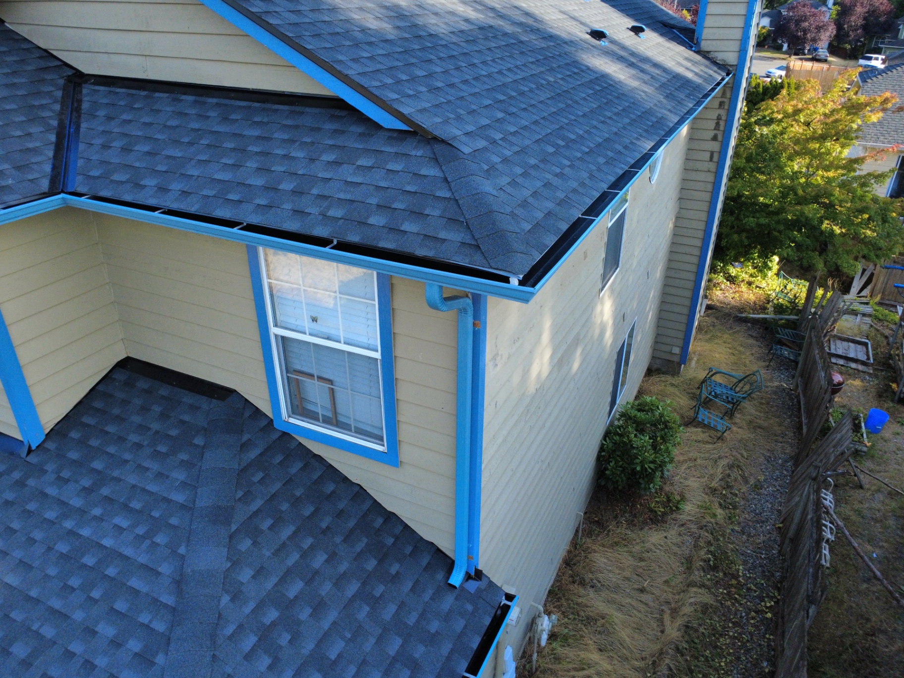 New dark gutters and blue downspout installed on a residential home